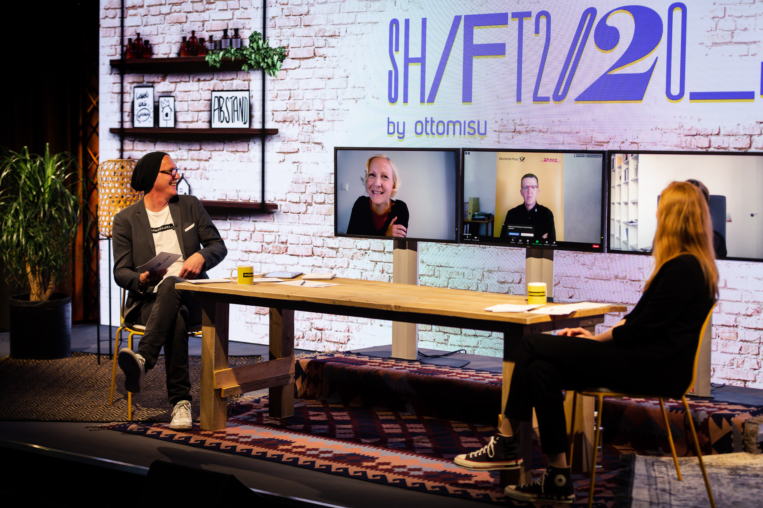 Ein Bild des Set Ups der SHIFT 2020, mit Lia und Helge, die sich mit digital zugeschalteten Teilnehmenden unterhalten.