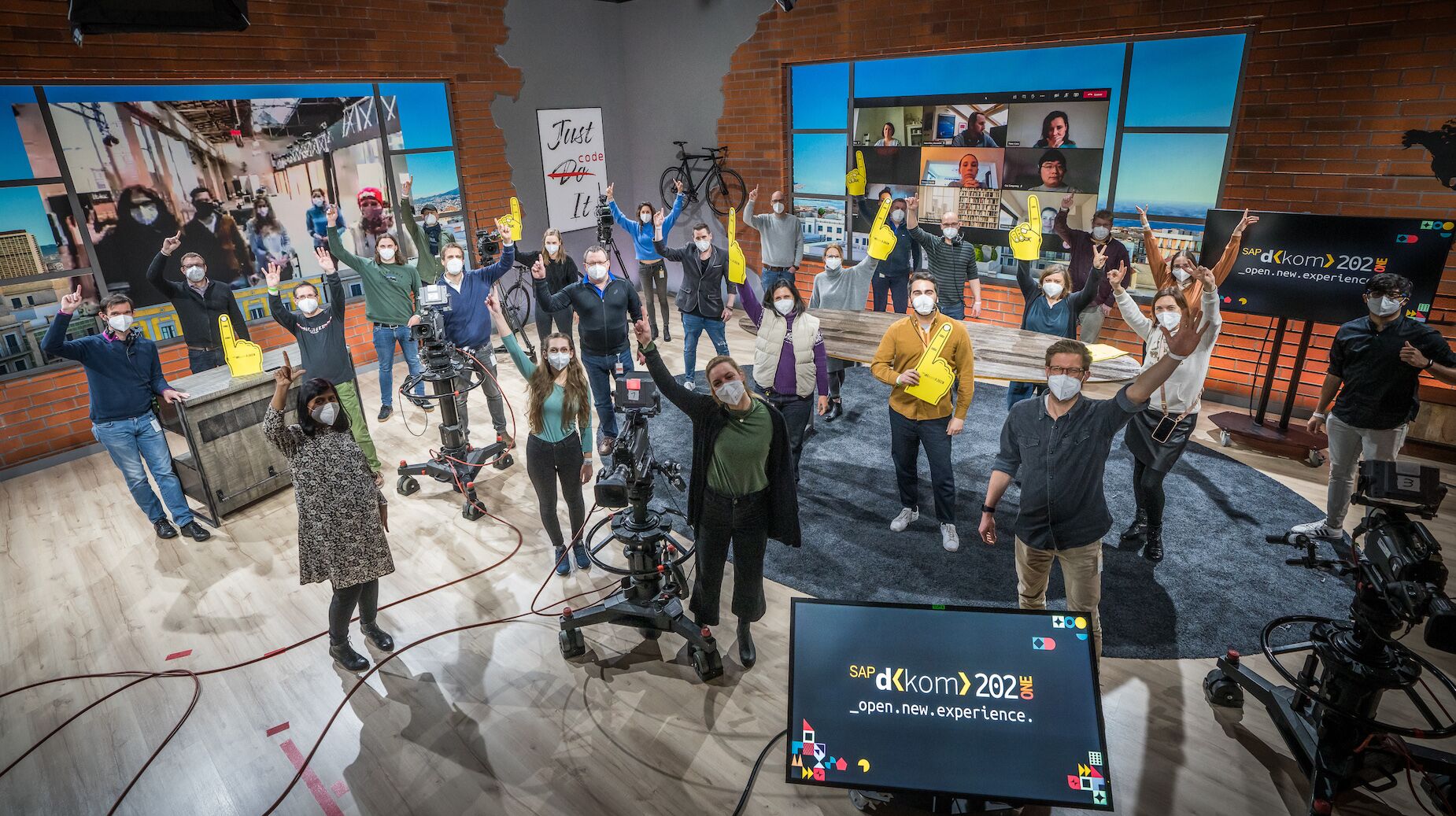 Gruppenfoto mit allen Beteiligten in einem Studio-Set. Kamerateam, Technikcrew und Moderator:innen feiern gemeinsam vor der virtuellen Bühne