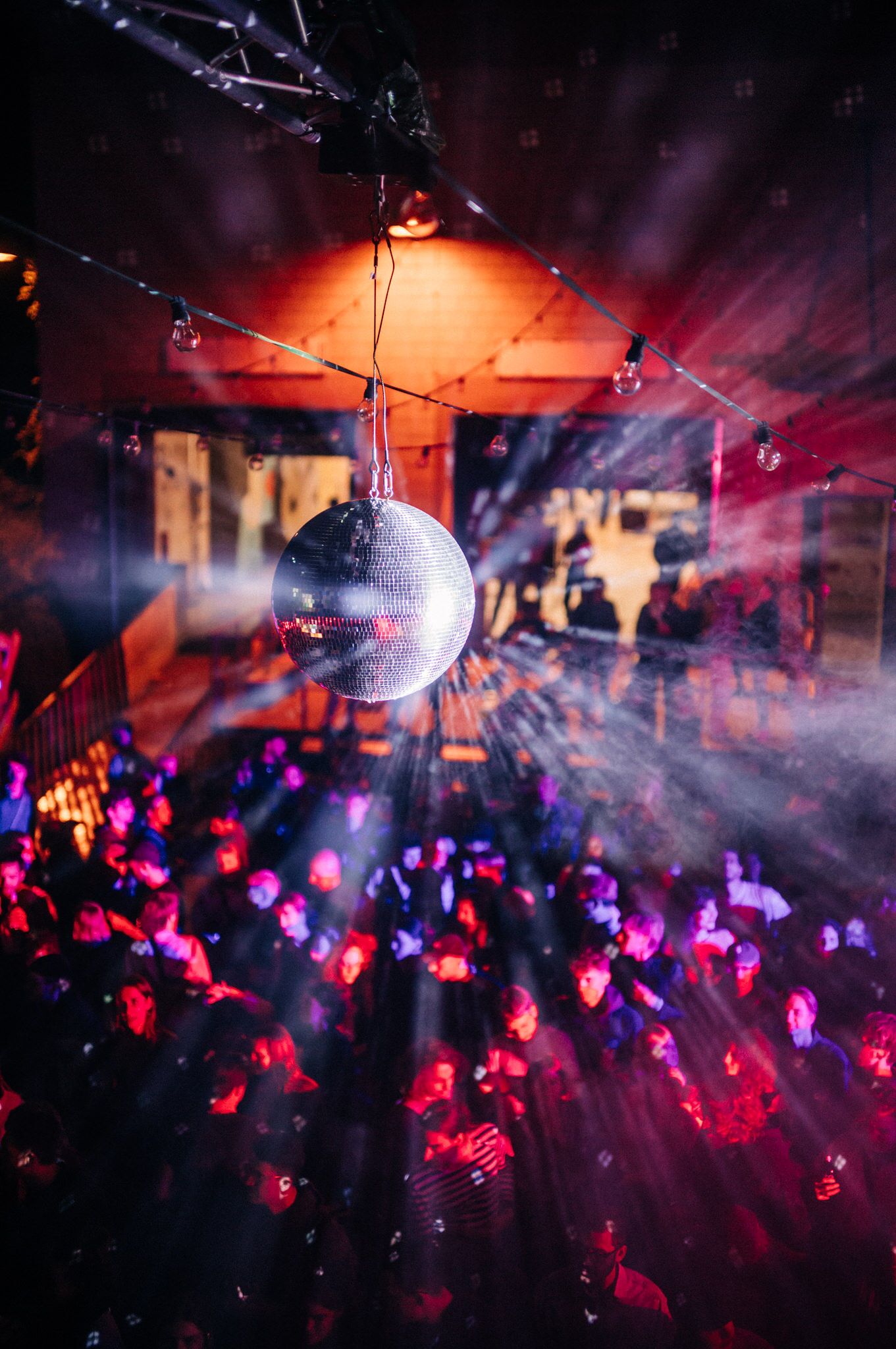 Discokugel mit mehreren Lichtreflexen und lila-rotem Licht