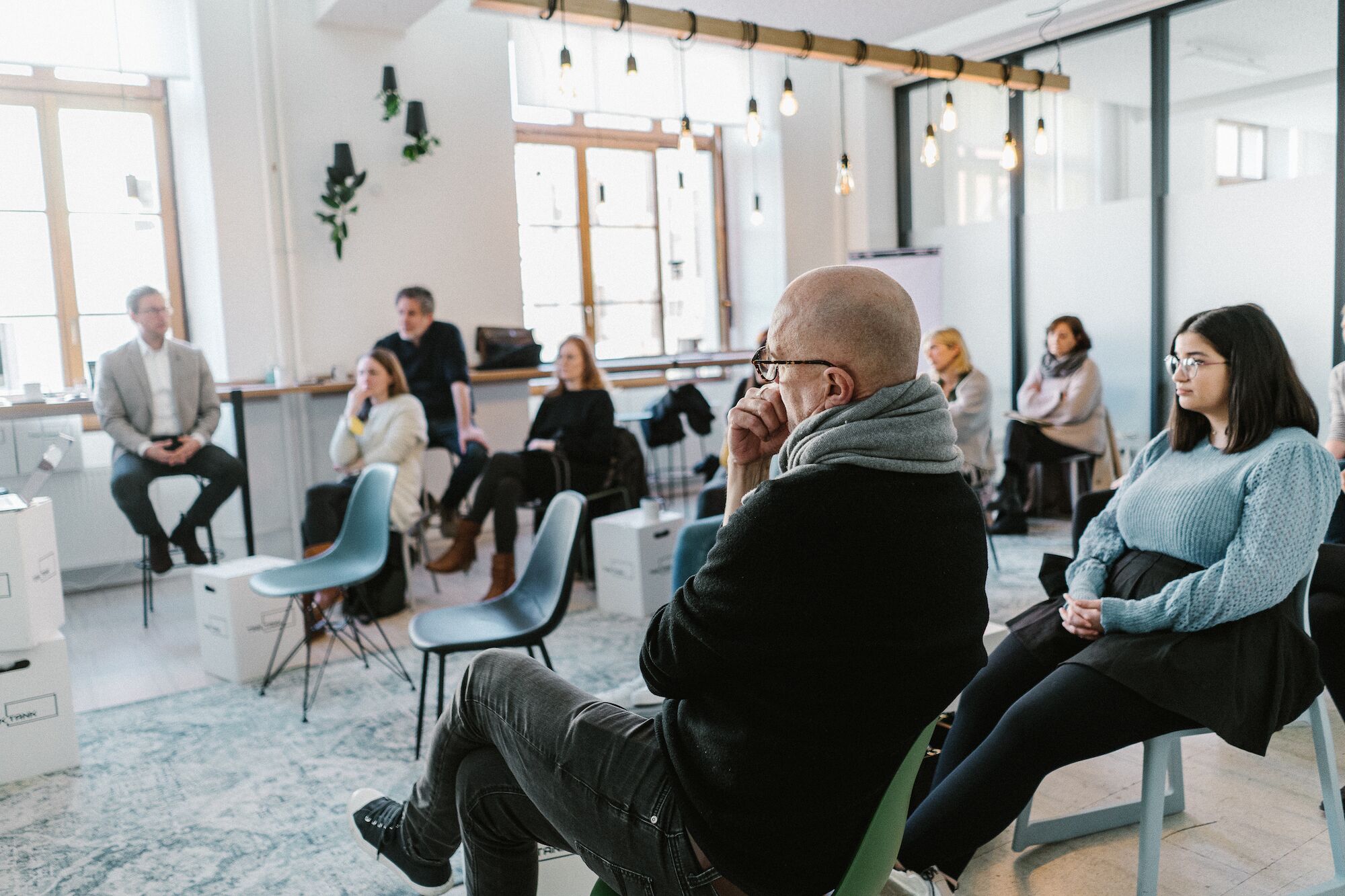Teamfoto, auf dem das ottomisu Team in einem Raum sitzt und gemeinsam einem Vortrag lauscht