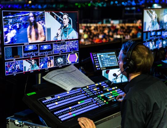 Ein Techniker steuert die Live-Regie eines Events mit zahlreichen Monitoren und Bildquellen.