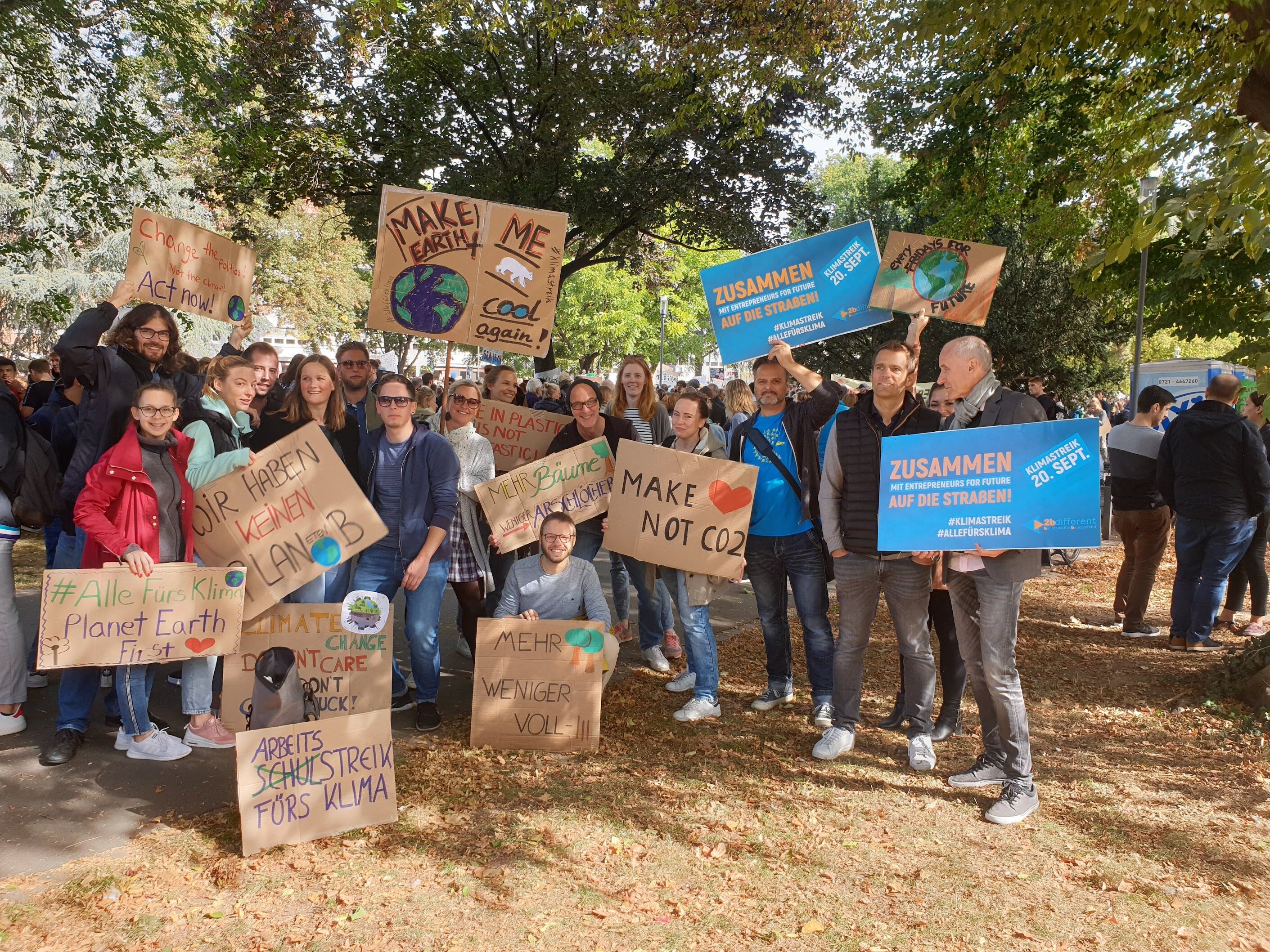 Das ottomisu Team auf einer Friday's For Future Demo mit beschrifteten Schildern und vielen Menschen.