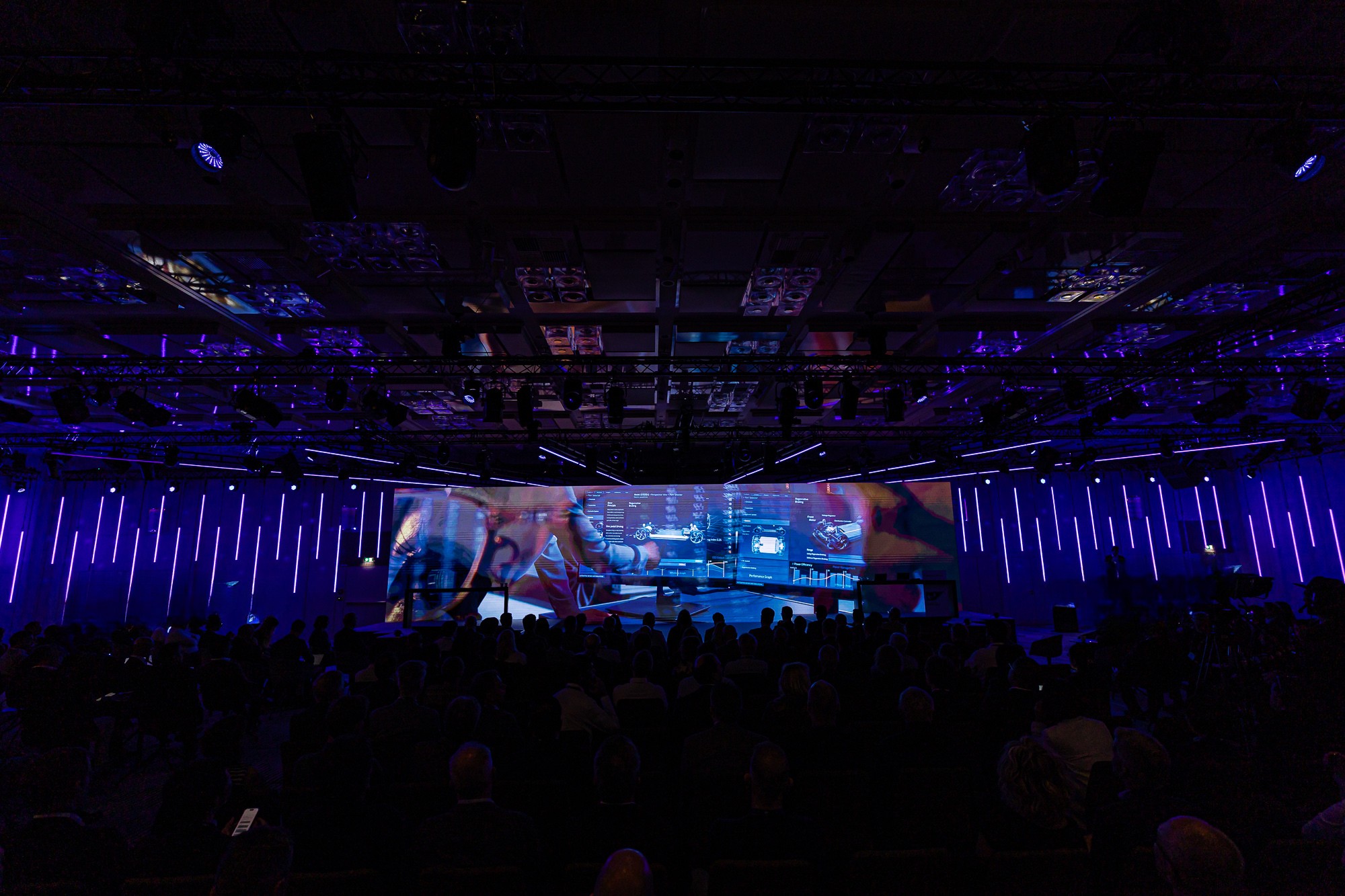 Große Eventfläche mit LED-Lichtinszenierung während einer Live-Präsentation, Publikum im Halbdunkel.
