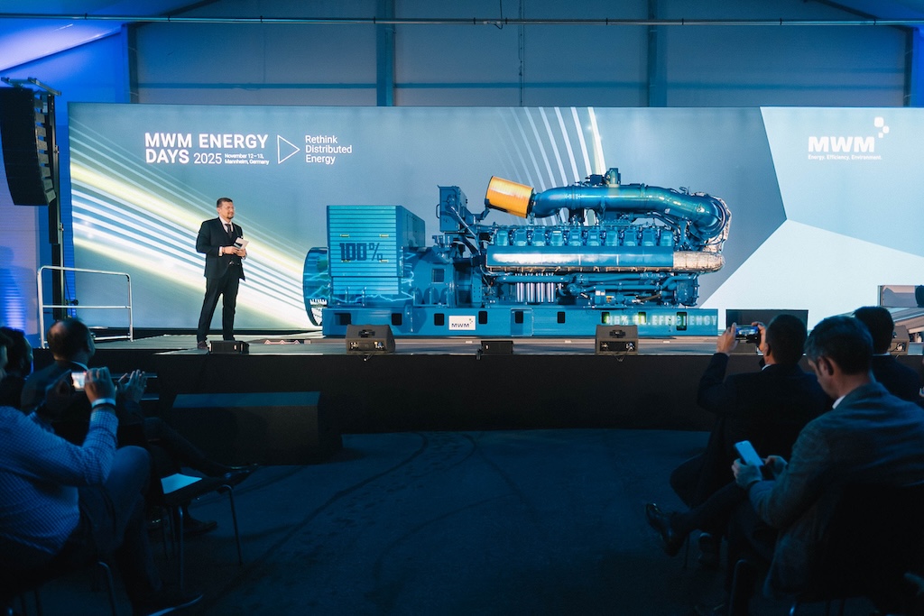 Technologischer Höhepunkt der Veranstaltung: Die Enthüllung eines großen blauen Aggregats auf der Bühne der MWM ENERGY DAYS 2025. Ein Moderator spricht vor dem Publikum.