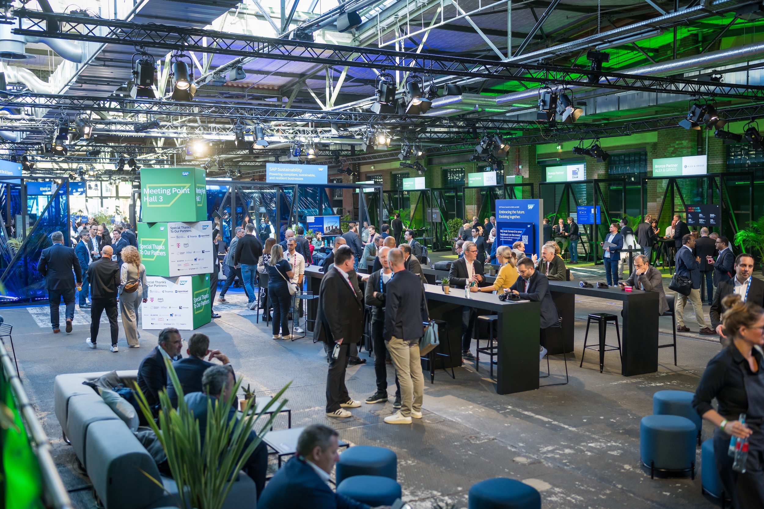 Networking-Bereich des SAP Partner Summit mit zahlreichen Besuchern an Stehtischen und Lounges. Beschilderung mit „Meeting Point Hall 3“ und Partnerlogos im Zentrum.