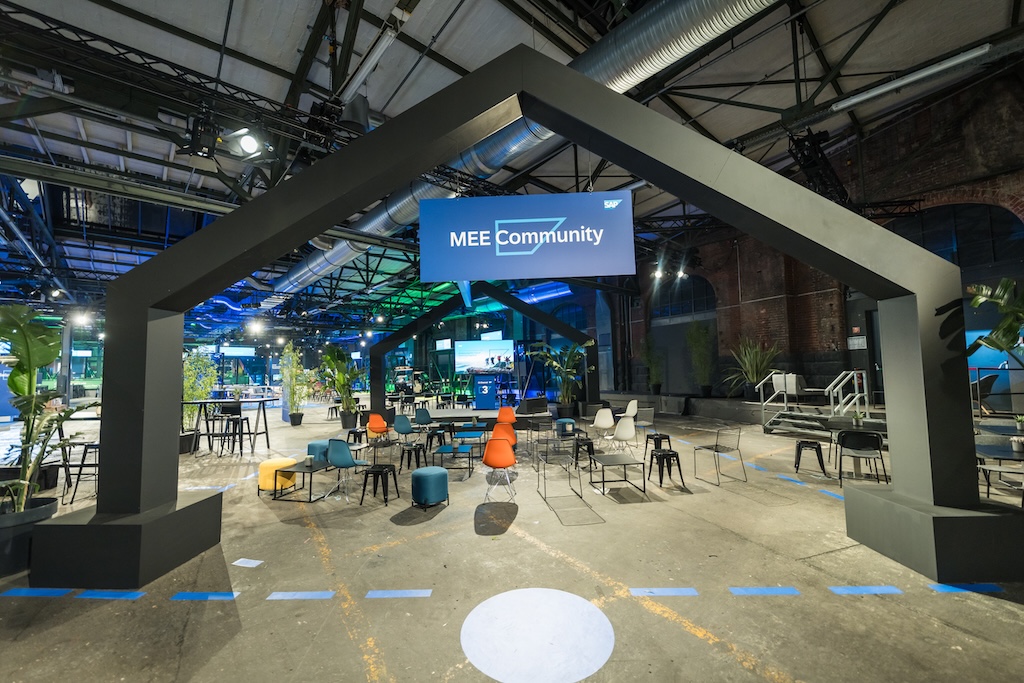 Der Bereich „MEE Community“ auf dem SAP Partner Summit, eingerahmt von einer markanten, hausförmigen Struktur. Bunte Sitzgelegenheiten und Pflanzen laden zum Austausch ein.