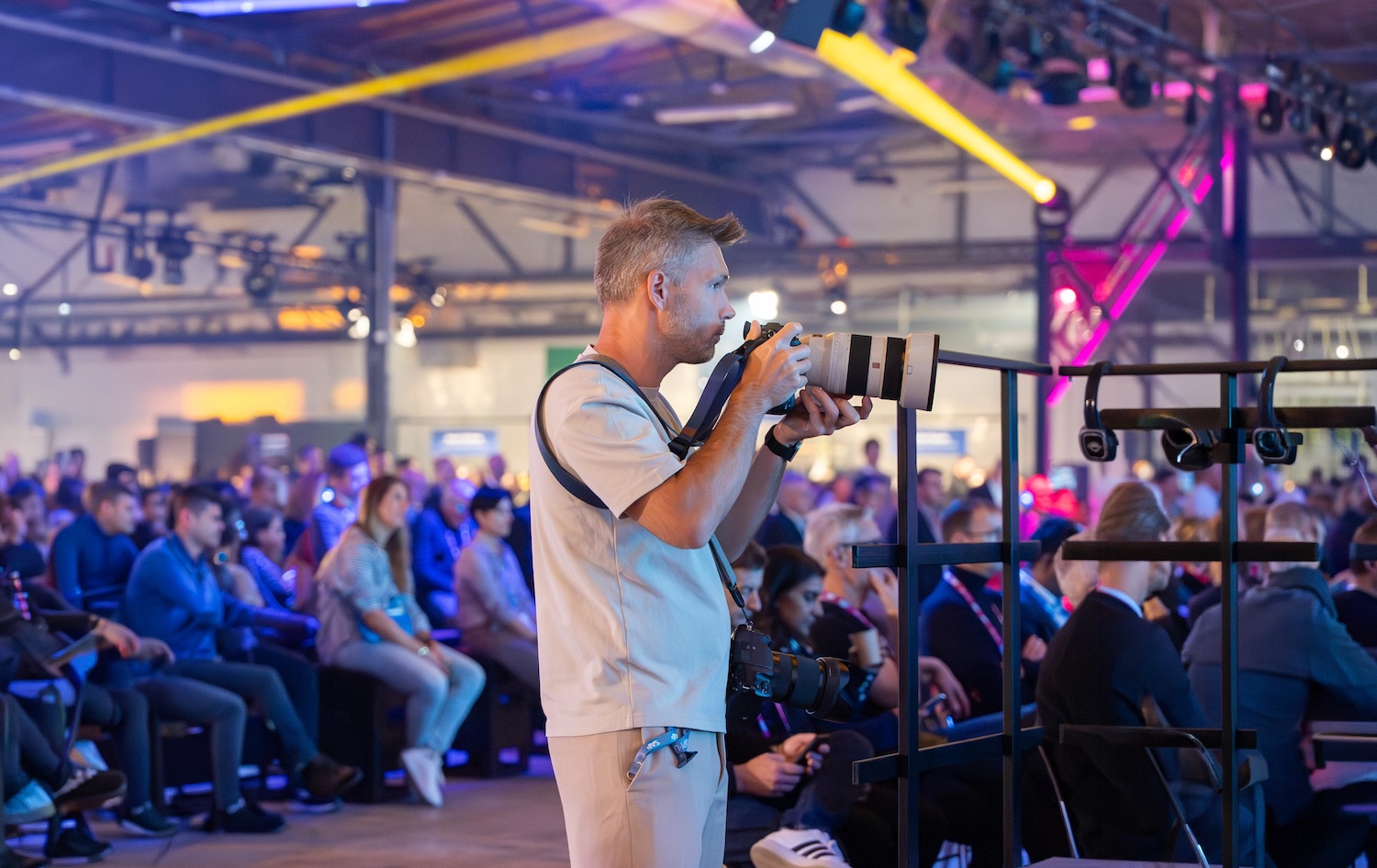 Photographer with a large telephoto lens captures an event while guests sit in the background.