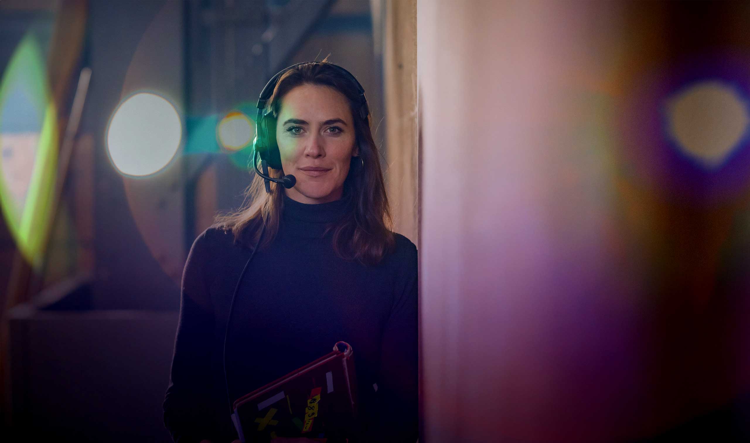 Event moderator backstage with headset and tablet during a live event with stage lighting effects